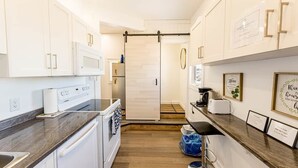 Eine moderne Küche mit weißen Schränken, einer Edelstahl-Dunstabzugshaube und einer Holzausziehtafel.