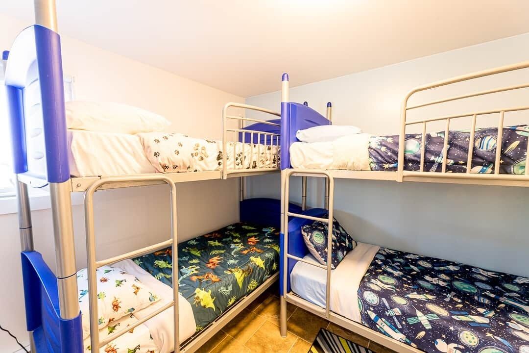 A dormitory room with bunk beds, each with a different patterned bedspread.