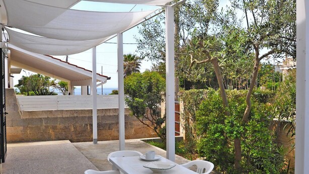 Un espace extérieur aménagé, abrité et doté d’une table et de chaises, entouré de verdure et offrant une vue panoramique.