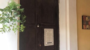 A dark wooden door with a sign, a hanging plant, and a small wall-mounted item. - CASA CABERNET ideal location for building memories (Parras de la Fuente)