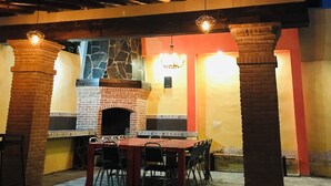An outdoor patio with a brick fireplace, a dining table with chairs, and a pergola structure. - CASA CABERNET ideal location for building memories (Parras de la Fuente)