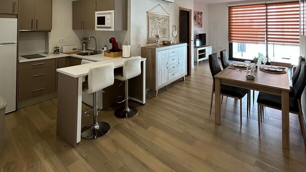 A modern kitchen with a dining area, wooden flooring, and recessed ceiling lights. - Apartment in A Hotel 'Apartamento Type 2 A' with Private Terrace, Wi-Fi and Air Conditioning (Puente Genil)