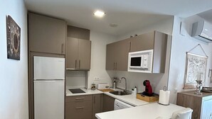Una cocina compacta con electrodomésticos modernos, un pequeño comedor y un cubo de basura.