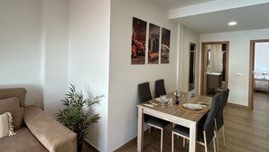 Una sala de estar moderna con sofá, mesa de comedor, sillas y una planta en maceta.