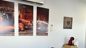 A dining area with a wooden table, chairs, a coffee machine, and wall art.
