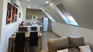 A modern loft apartment with a dining area, kitchen, and a cozy seating area with a sofa and pillows.