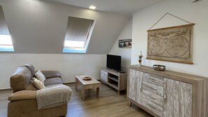 A loft-style room with a sofa, TV, wooden cabinet, and a world map on the wall.