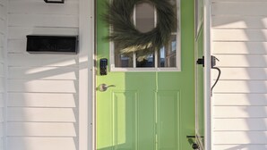 A green door with a wreath, a mailbox, and a welcome mat. - Boho abode Uptown Maumee by River-GREEN Side! (Maumee)