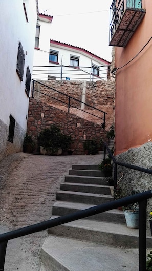 A narrow stairway leading up to a building with stone walls and metal railings.