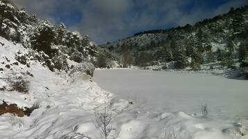 Un paisaje nevado con un lago congelado, árboles y un cielo despejado.