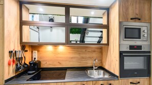 A compact kitchen with wooden cabinets, a stainless steel sink, and a built-in oven. - M Alg310b Amplio y Moderno Loft con Terraza Priv (Madrid)