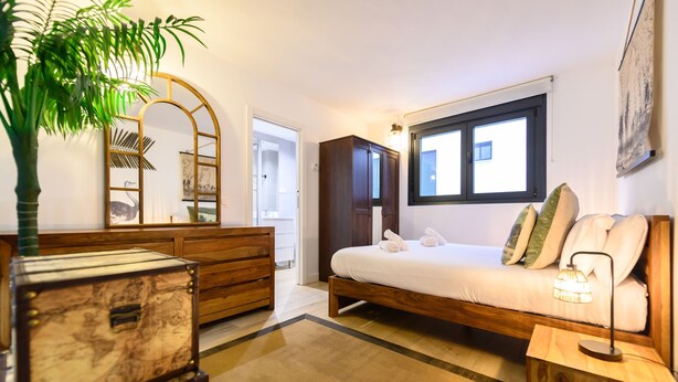 A bedroom with a bed, dresser, mirror, and a potted plant. - M Alg310b Amplio y Moderno Loft con Terraza Priv (Madrid)