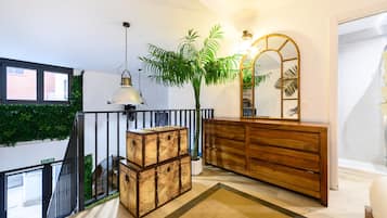Een modern interieur met een trap, een houten dressoir, een grote spiegel en een potplant.
