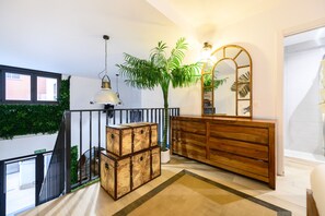 Een modern interieur met een trap, een houten dressoir, een grote spiegel en een potplant.