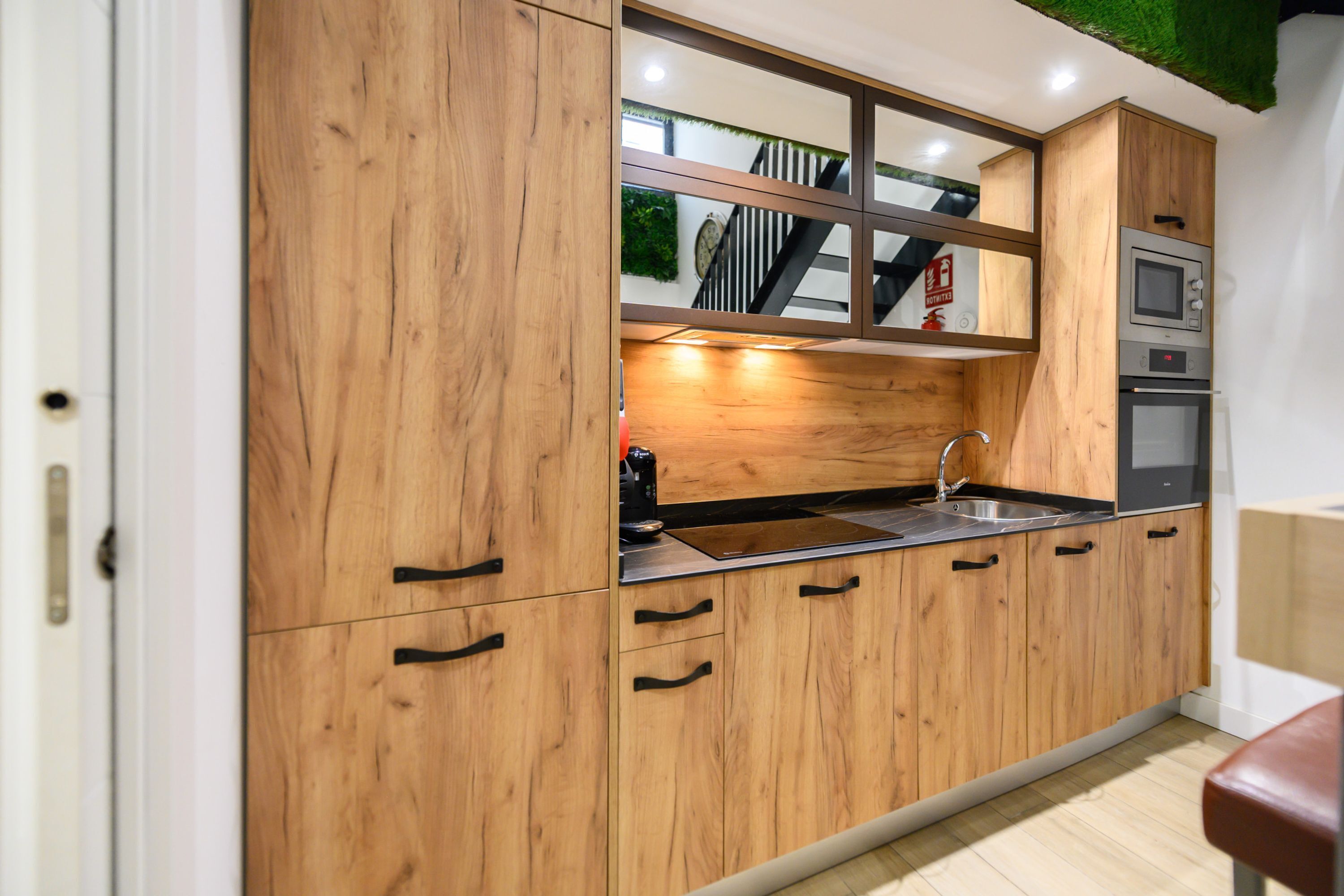Una cocina con armarios de madera, un lavamanos de acero inoxidable y un microondas.