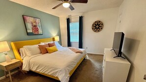 A bedroom with a bed, a nightstand, a TV, and a ceiling fan. - Tropical Funky Oasis- near downtown and islands. Pet Friendly! (Savannah)