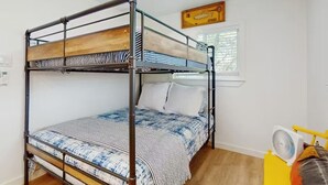 Un letto a castello con copripiumino a righe, un cuscino bianco e una ventola su un supporto giallo.