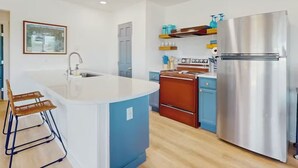 Una cucina moderna con un'isola centrale, un frigorifero in acciaio inossidabile e mobili azzurri.
