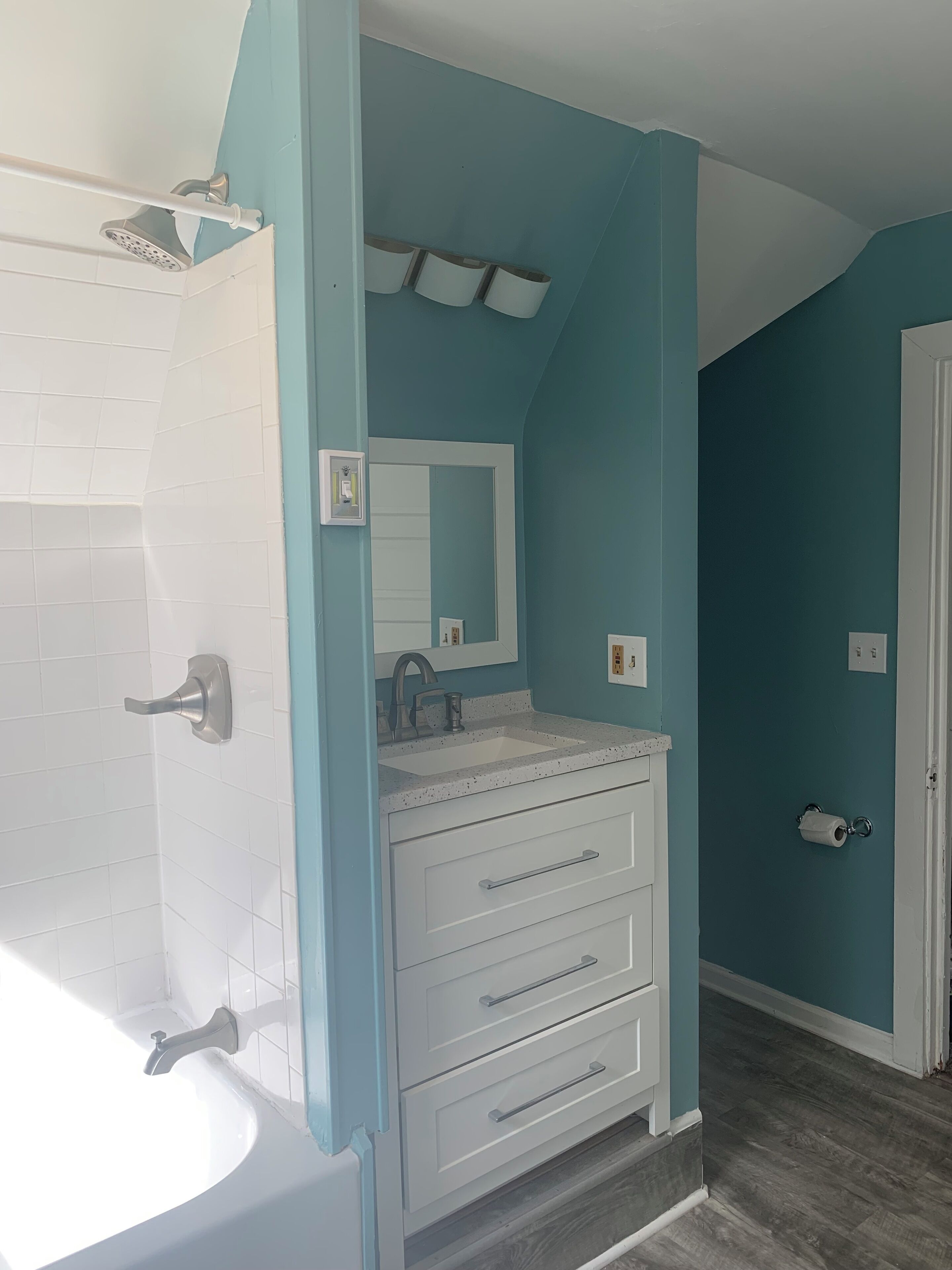 Un baño con lavamanos blanco, espejo y ducha.