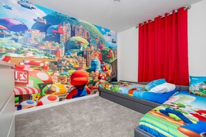 Un dormitorio con un mural al estilo de Mario, una cortina roja y una cama con ropa de cama colorida.