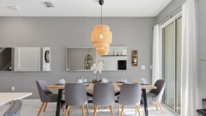 Et moderne spiseområde med et træbord, grå stole og en hængende lampe.