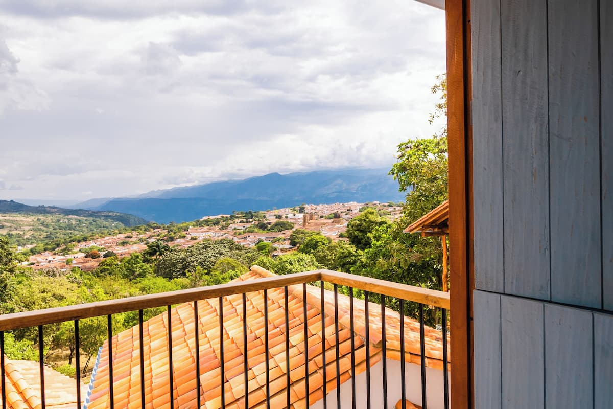 Un balcón con techo de tejas que ofrece vistas a un pueblo y montañas.