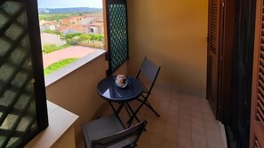 A small balcony with a table and chairs, a view of a residential area, and a door with a window. - Agave - Two Bedroom Apartment, Sleeps 5 (Olmedo)