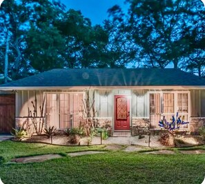 A single-story house with a red front door, a covered porch, and a small garden with various plants. - Sleeps 14 on the River! Free Kayaks -by Whitewater (Canyon Lake)