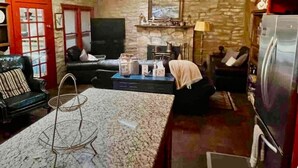 Una sala de estar acogedora con chimenea, pared de piedra y cocina moderna con refrigerador.
