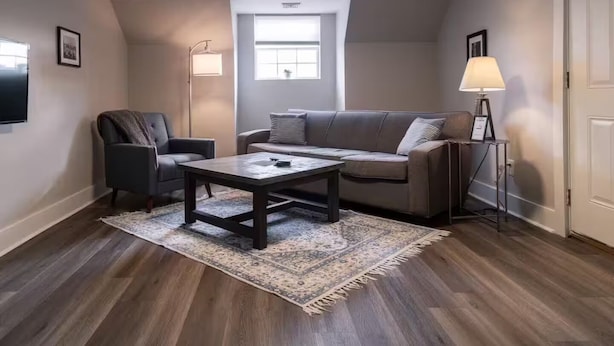 En moderne stue med sofa, lænestol, sofabord og lampe.