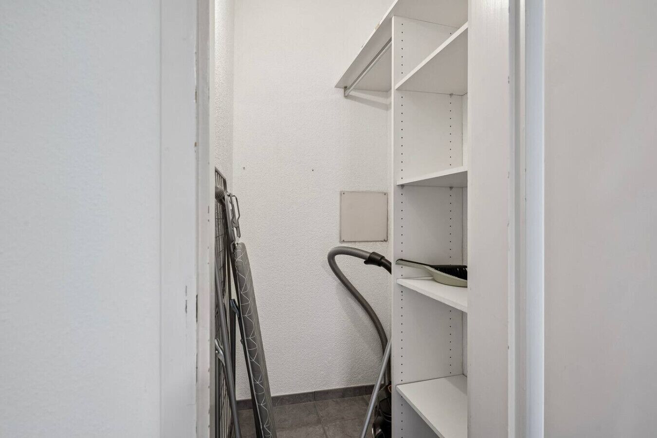 A narrow hallway with white walls and shelves.