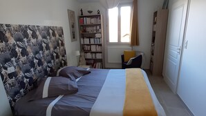 Une chambre à coucher avec un lit, un bureau, une chaise, une bibliothèque et une fenêtre.