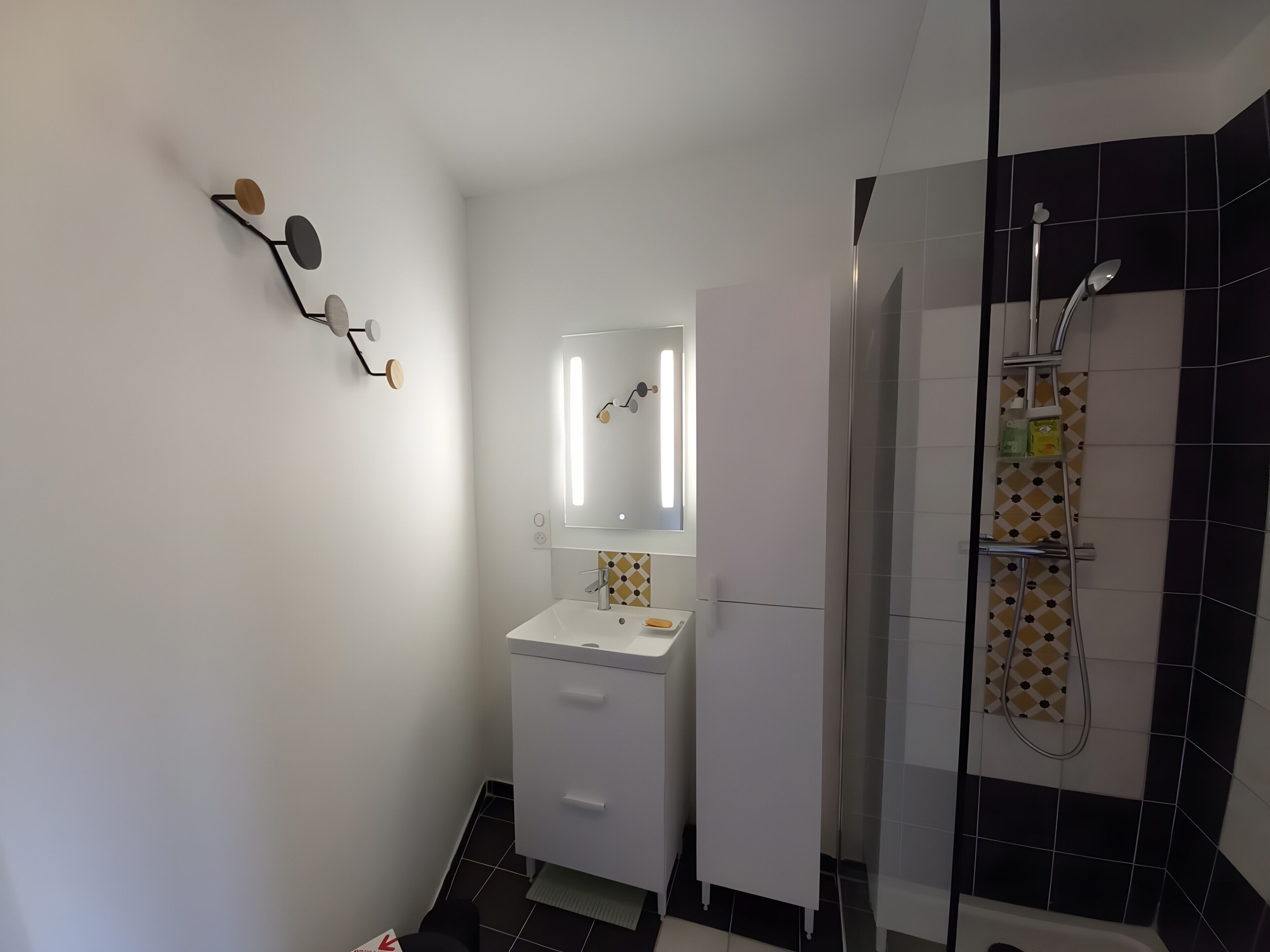 A bathroom with a white sink, mirror, and shower.