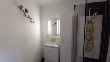 A bathroom with a white sink, mirror, and shower.