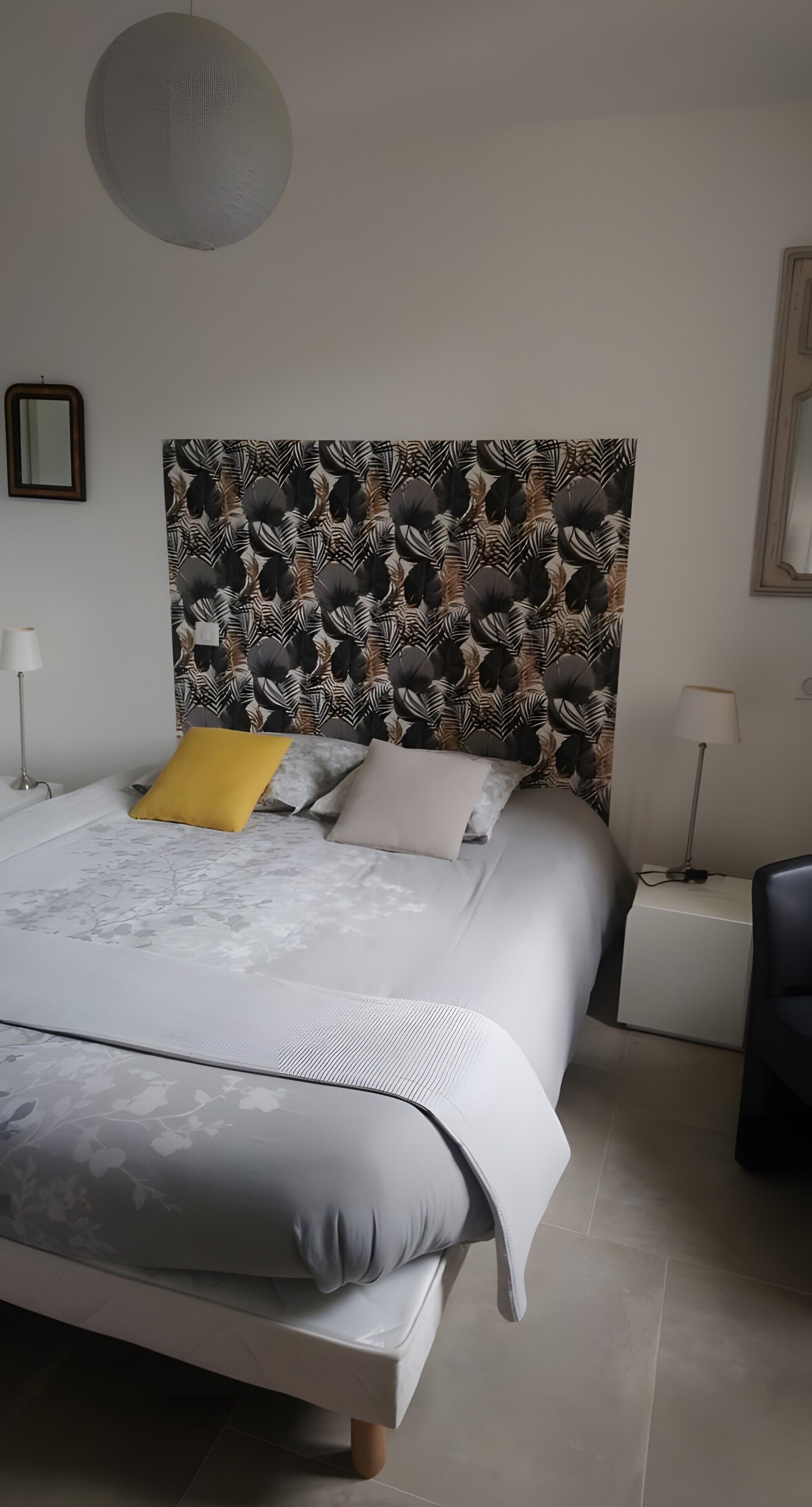 Une chambre à coucher moderne avec un grand lit, une tête de lit à motifs, une table de chevet et une chaise.