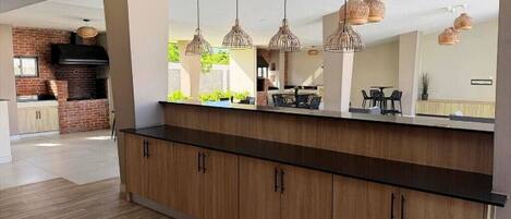 A modern kitchen with wooden cabinets, a black countertop, and hanging wicker pendant lights.