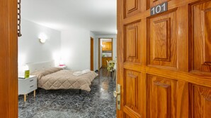 A hotel room with a bed, a nightstand, a desk, a chair, and a wooden door with the number 101. - Holiday Studio 'Estudio Alenia' (San Marcos)
