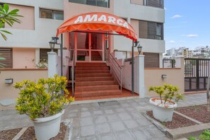Ingresso di un edificio con una scala, piante in vaso e un cartello con su scritto 'AMARCA'.