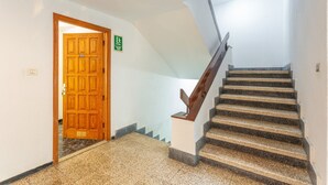 A staircase with a wooden handrail, a carpeted floor, and a door with a wheelchair accessibility sign. - Holiday Studio 'Estudio Alenia' (San Marcos)