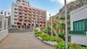 A multi-story hotel with balconies, a paved walkway, and a hillside backdrop. - Holiday Studio 'Estudio Alenia' (San Marcos)