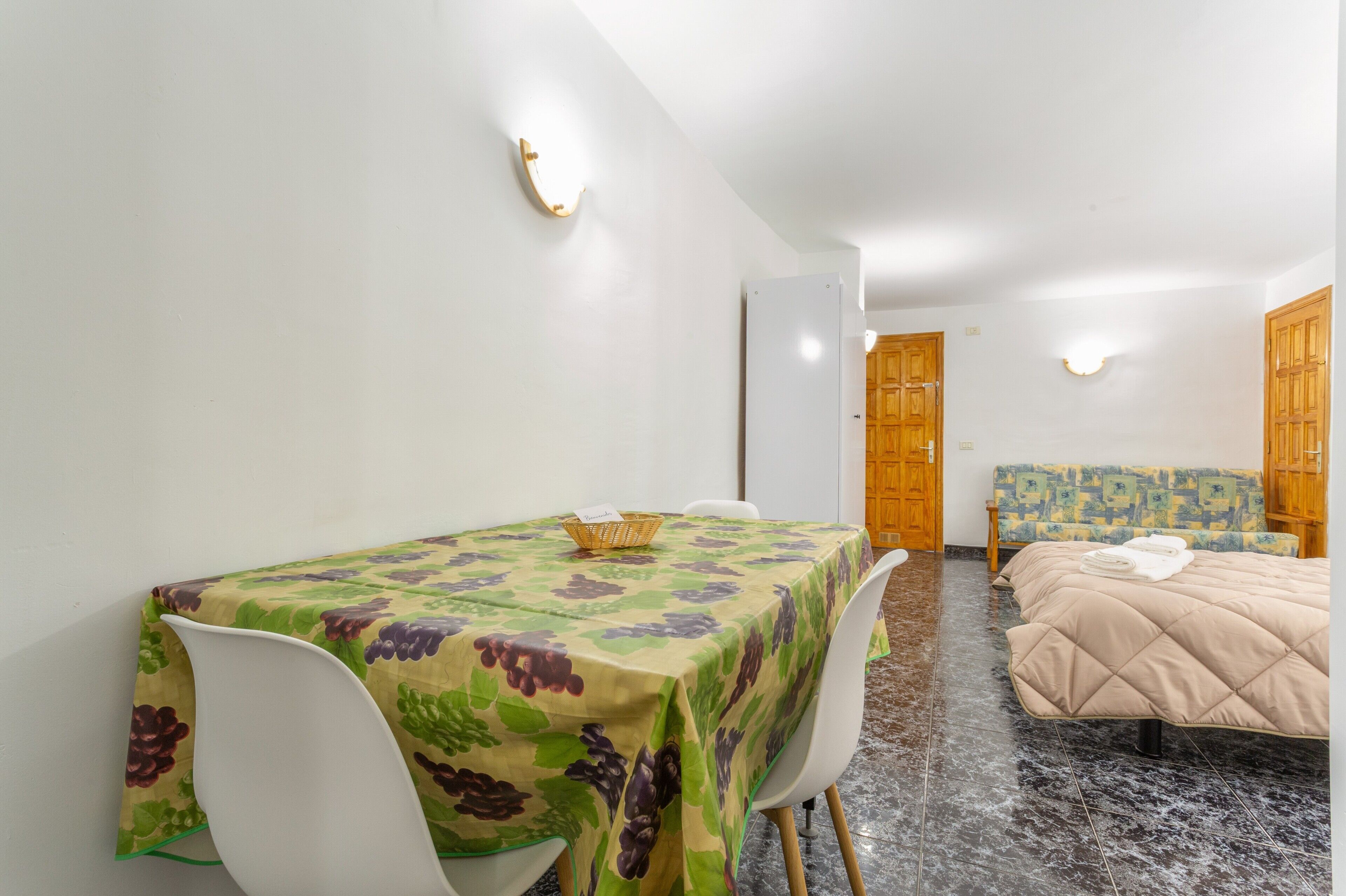 A room with a dining table, chairs, a bed, and a small sofa.