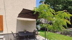 An outdoor patio with a table and chairs, a pergola providing shade, and a small tree. - Spacious 6-bedroom apartment in welcoming Budapest with AC (Budapest)