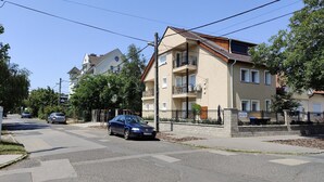 A residential street with a two-story apartment building, a car parked on the side, and a pedestrian crossing. - Spacious 6-bedroom apartment in welcoming Budapest with AC (Budapest)