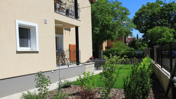 A residential building with a balcony, a small garden with various plants, and a paved area. - Spacious 6-bedroom apartment in welcoming Budapest with AC (Budapest)