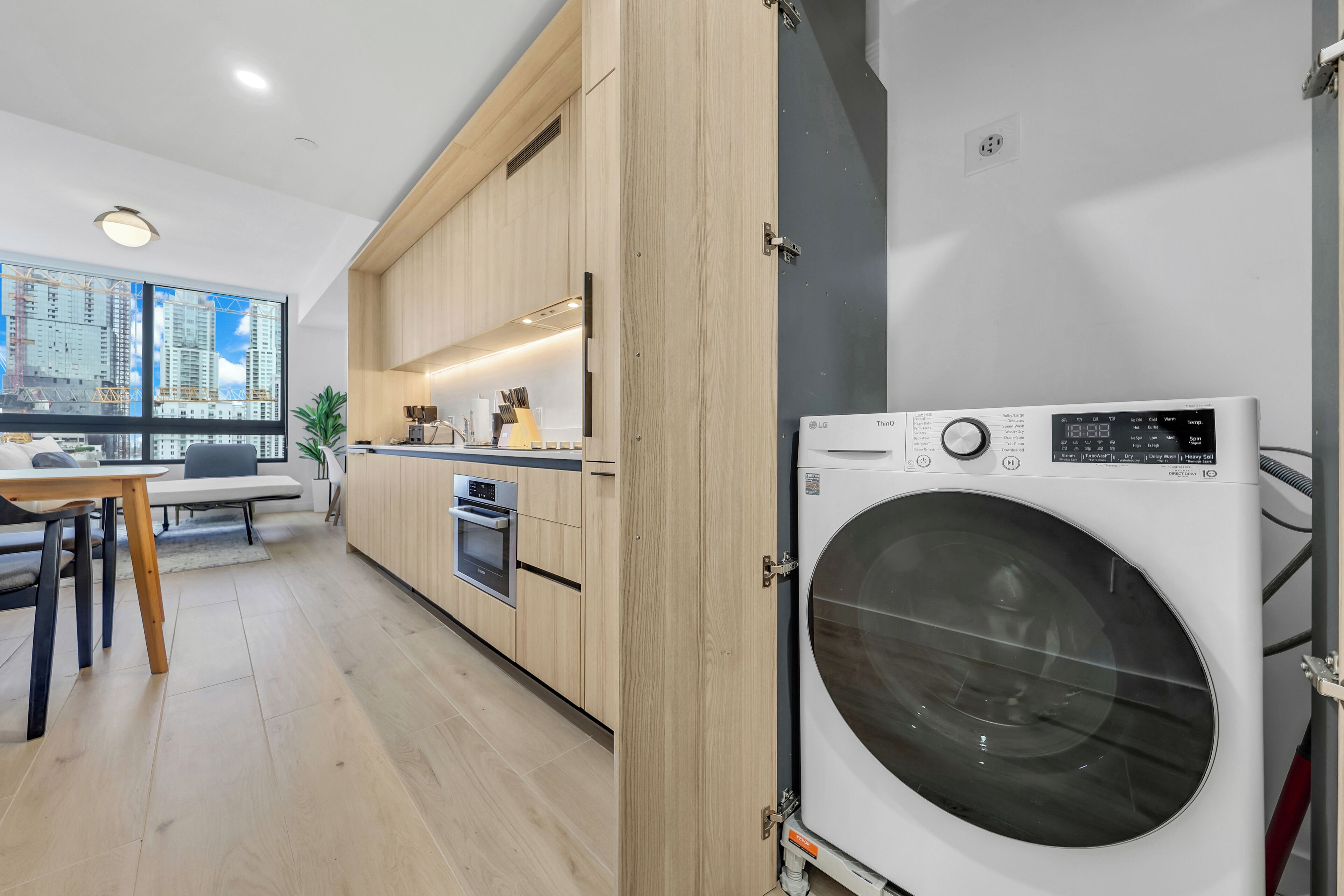 Una cocina moderna con armarios de madera, horno empotrado y un amplio ventanal con vistas a la ciudad.