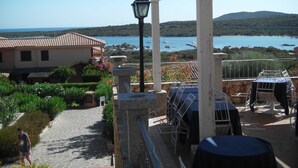 En terrasse med havudsigt, en pergola og udendørs møbler.