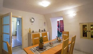 Ein Essbereich mit einem Holztisch, Stühlen, einer Ananas als Mittelstück und einer Uhr an der Wand.