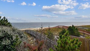 A coastal view with a wooden boardwalk, beach, and ocean. - 5BR Beach Home | Steps to Ocean | Sleeps 12! (North Bethany Beach)