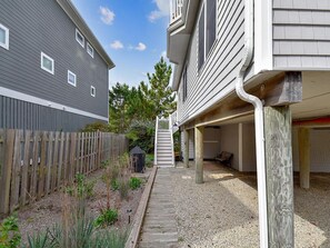 Ein Wohnhaus mit überdachter Terrasse, einer Holzterrasse und einer Schotterauffahrt.