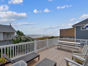 A deck with white railings, a bench, and chairs overlooking the ocean. - 5BR Beach Home | Steps to Ocean | Sleeps 12! (North Bethany Beach)